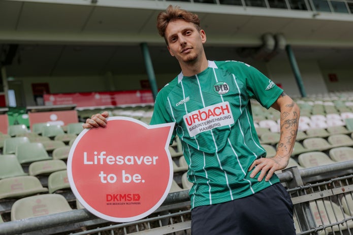 Zu sehen ist der Spieler Fabian Istefo mit einem Schild der DKMS "Lifesaver to be". 