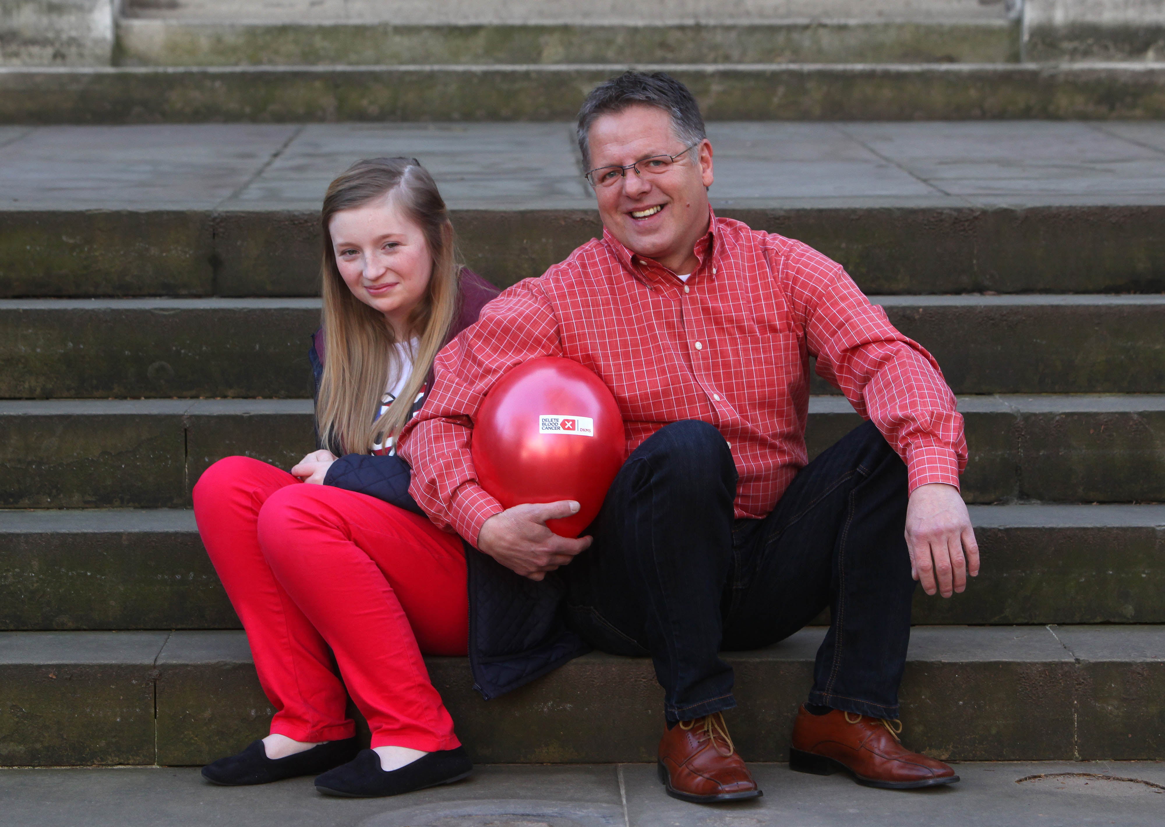 Ein Mann und ein Mädchen sitzen auf einer Treppe und halten einen Luftballon