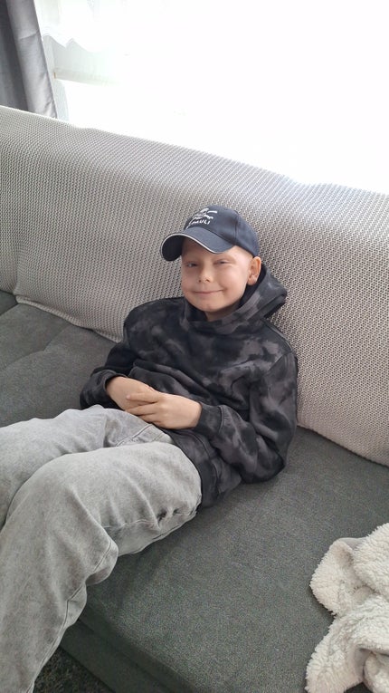 Dean sitzt auf dem Sofa und schaut in die Kamera