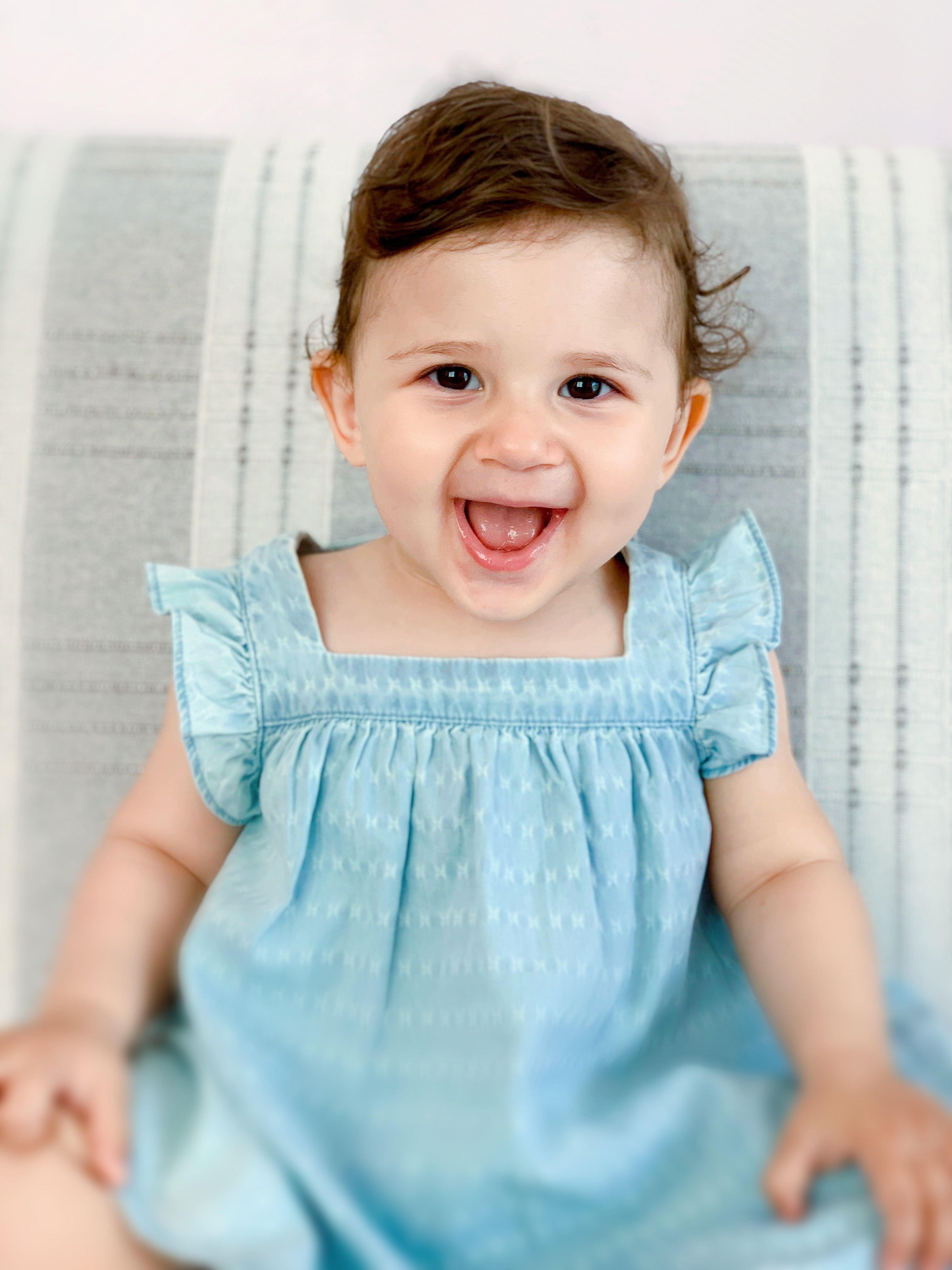 Die kleine Liya ist 18 Monate alt, sie trögt ein blaues Kleid und lächelt