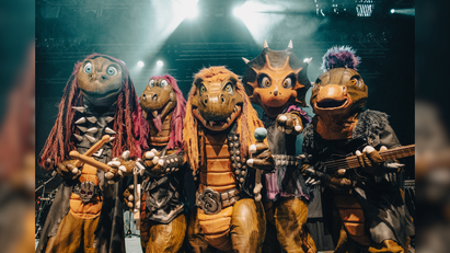 Eine Gruppe von Menschen in Dinosaurierverkleidung mit Instrumenten.