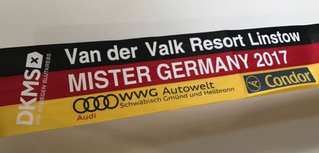 Nahaufnahme eine Deutschland Flagge mit dem Aufdruck Van der Valk Resort Linstow Mister Germany 2017. Link auf der Flagge ist ein DKMS Logo