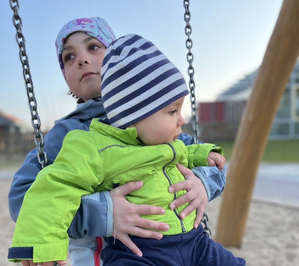 Ein Kind hält ein Baby auf einer Schaukel