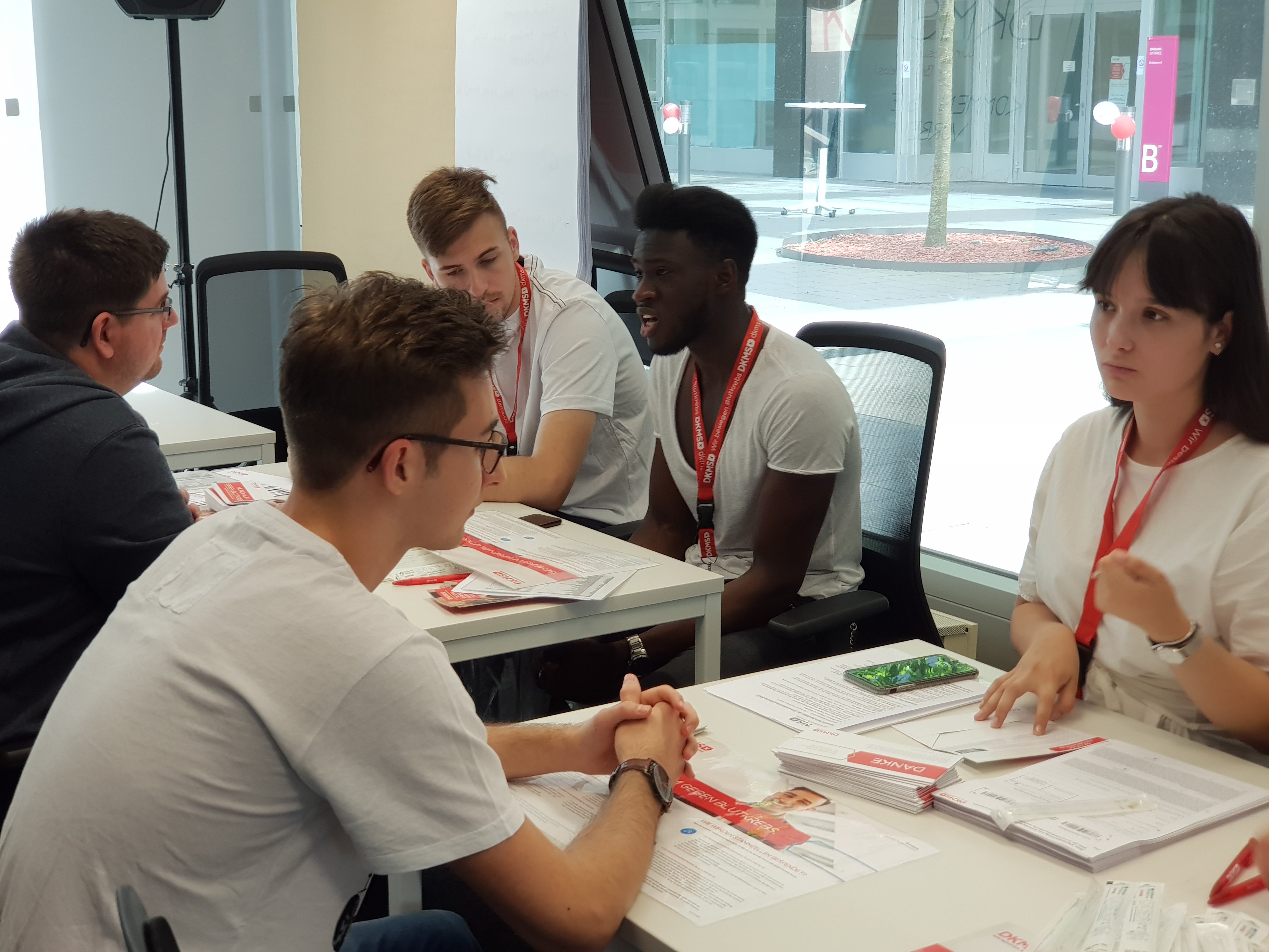 Eine Gruppe von Menschen, die sich gegenüber an Tischen sitzen