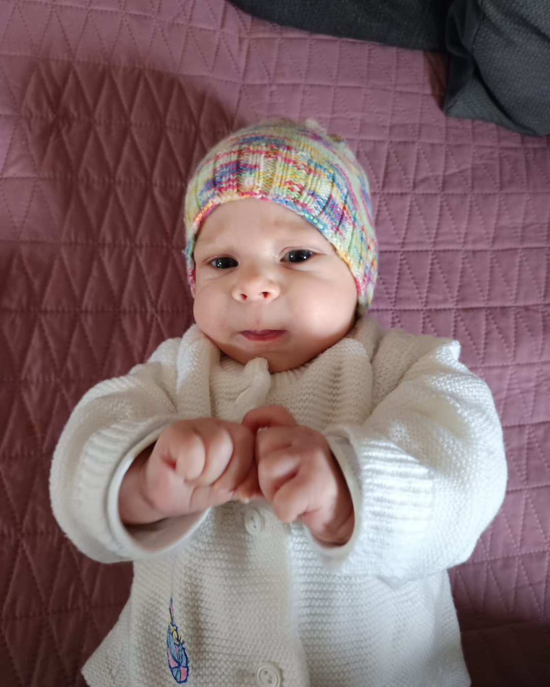 Ein Baby trägt eine Strickmütze und einen Pullover