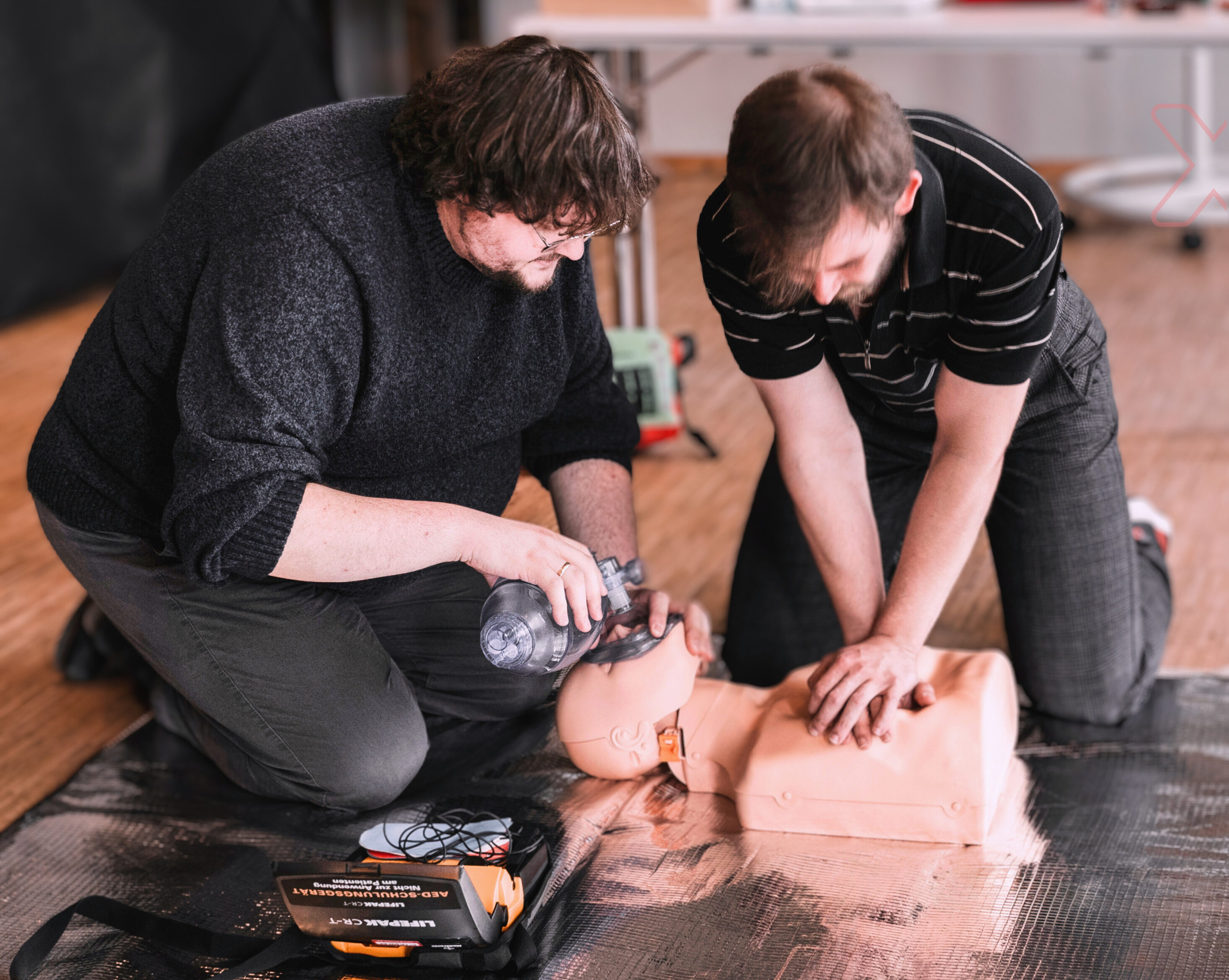 Zwei junge Männer üben Wiederbelebungsmaßnahmen an einer Übungspuppe 