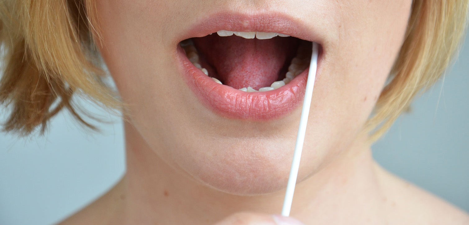 Frau nimmt eine Speichelprobe mit einem Wattestäbchen 