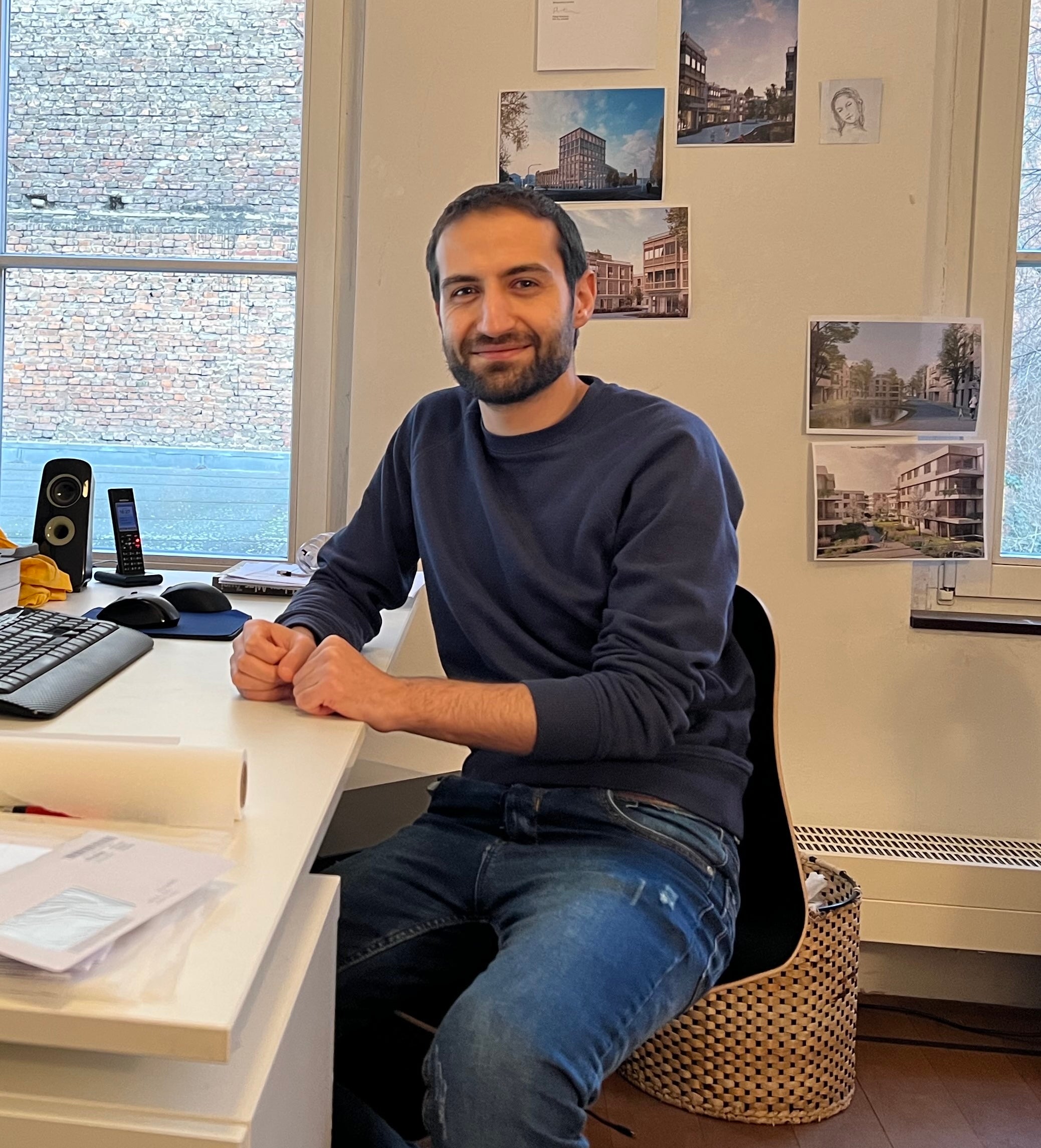 Mann sitzt am Schreibtisch und lächelt in die Kamera