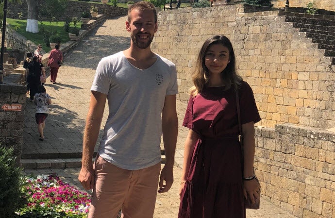 Christopher und Elvira stehen vor einer Steinmauer