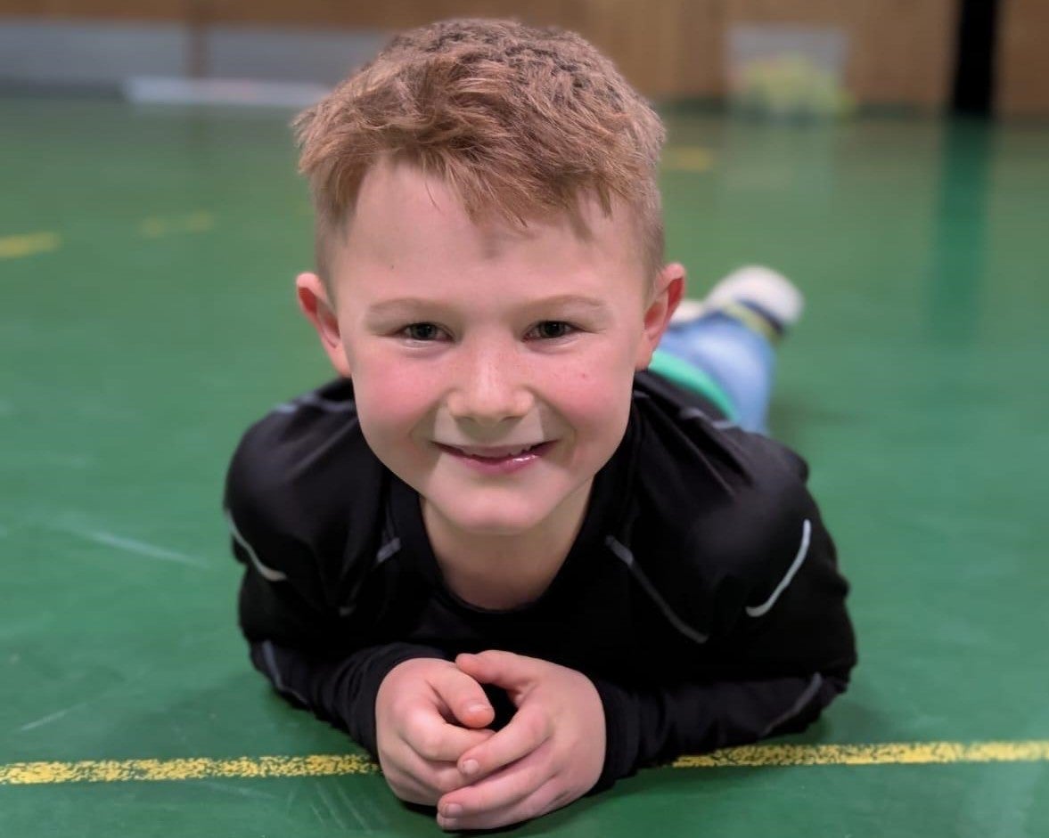 Ein Junge liegt auf dem Bauch auf einem grünen Boden