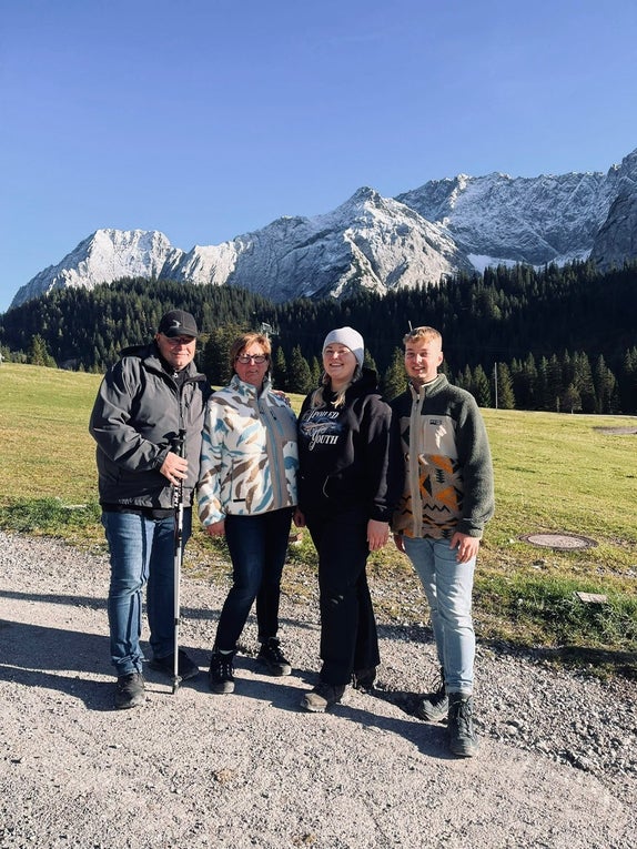 Wir sehen Ilona mit ihrem Mann und ihren zwei Kindern in der Natur. 