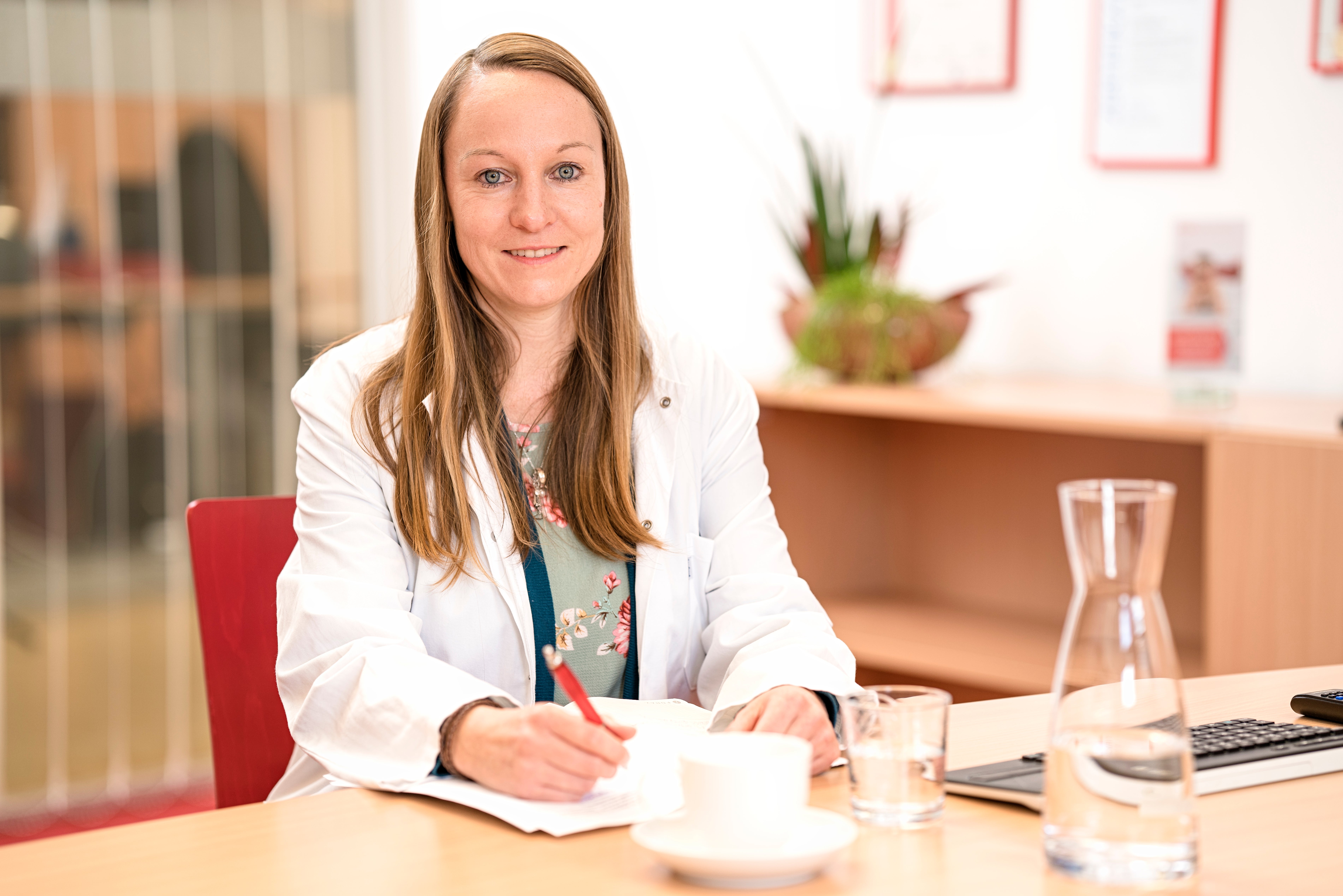 Anja Sauer sitzt an einem Tisch und schreibt auf ein Papier