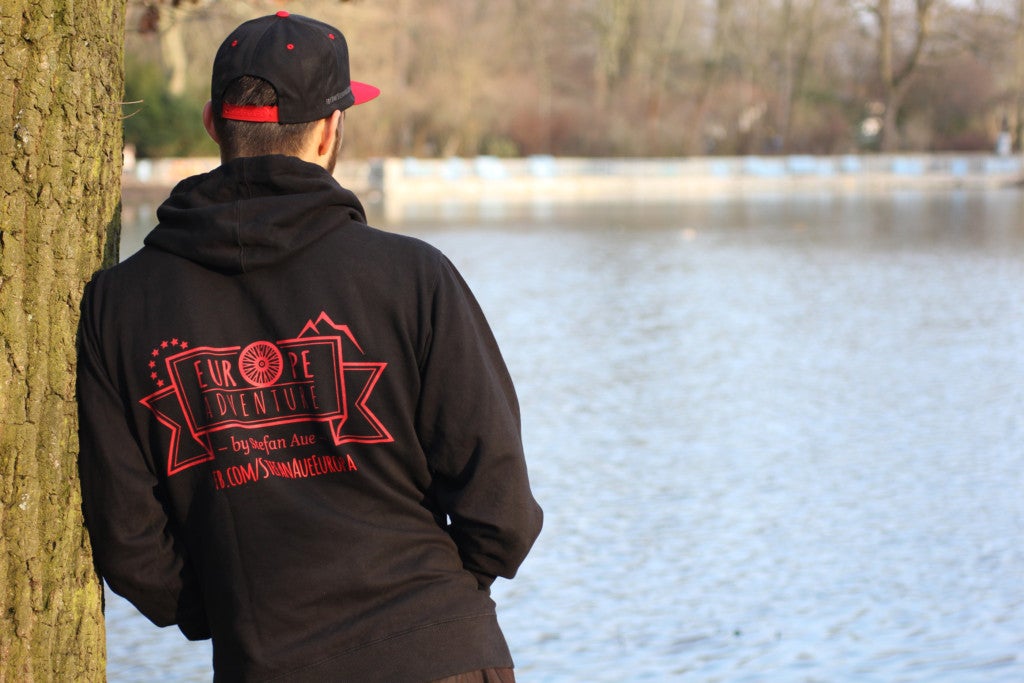 Ein Mann steht am Wasser. Er steht mit dem Rücken zur Kamera.