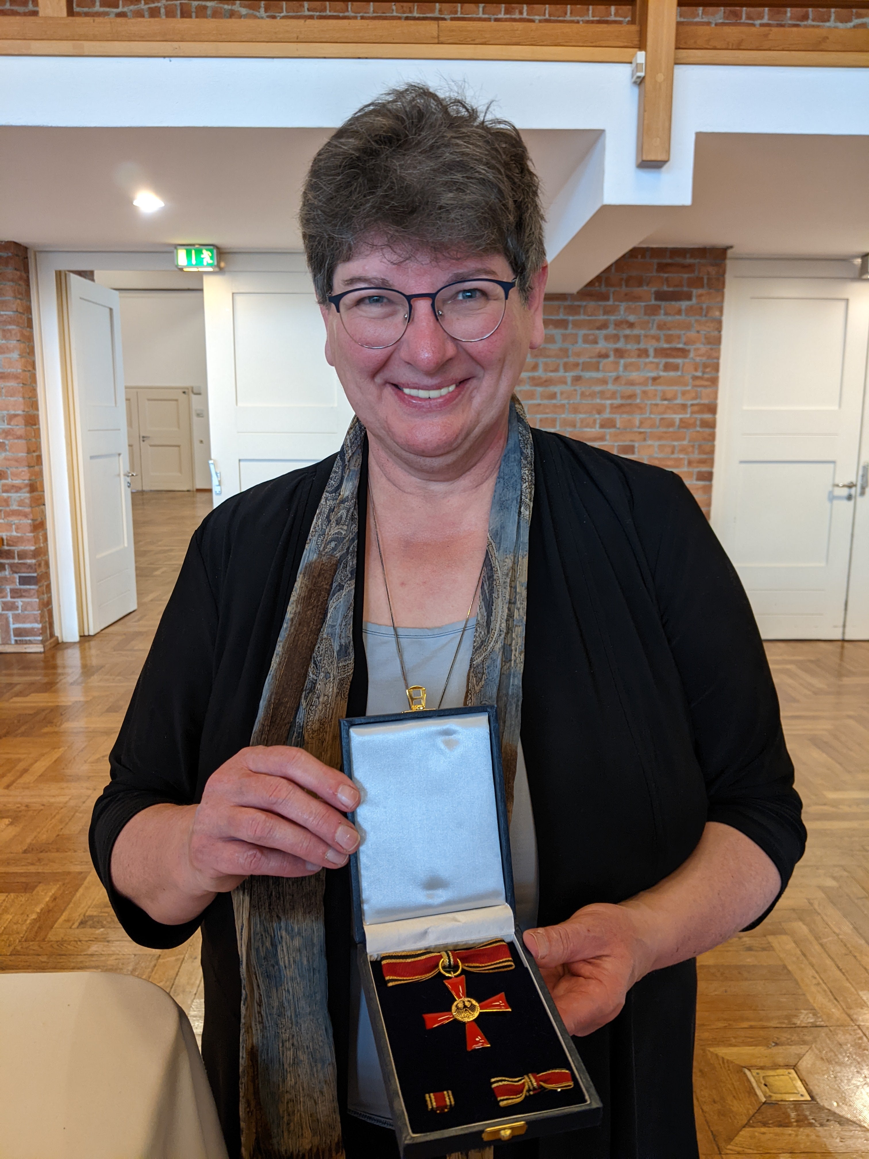 Eine Frau hält eine Schachtel mit einem Bundesverdienstkreuz