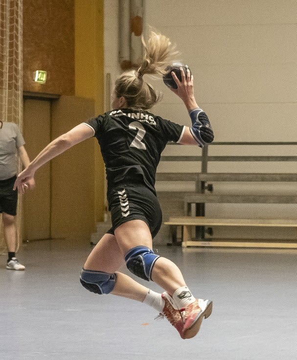Eine blonde Frau mit Zopf bei einem Wurf mit einem Handball. 