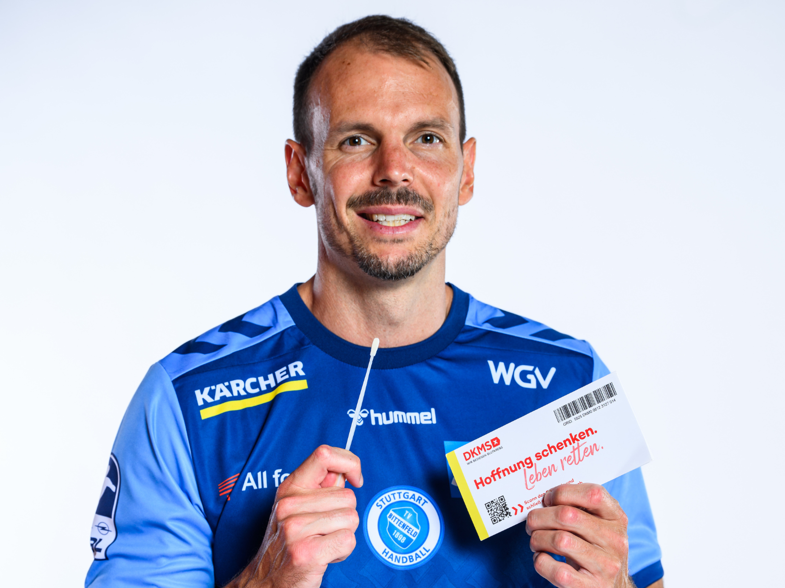Ein TVB Spieler hält eine DKMS Registrierungskarte hoch