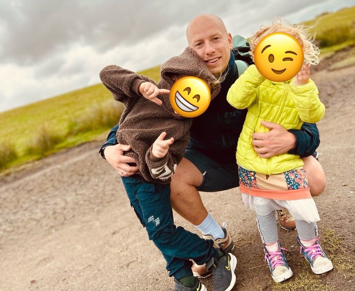 Ein Mann hält zwei Kinder in den Armen.