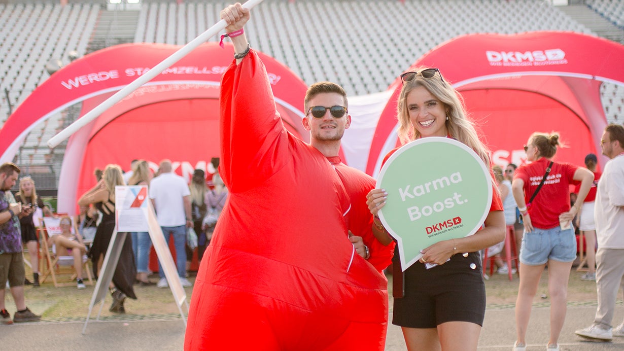Ein Mann und eine Frau in rotem Gewand halten ein Schild