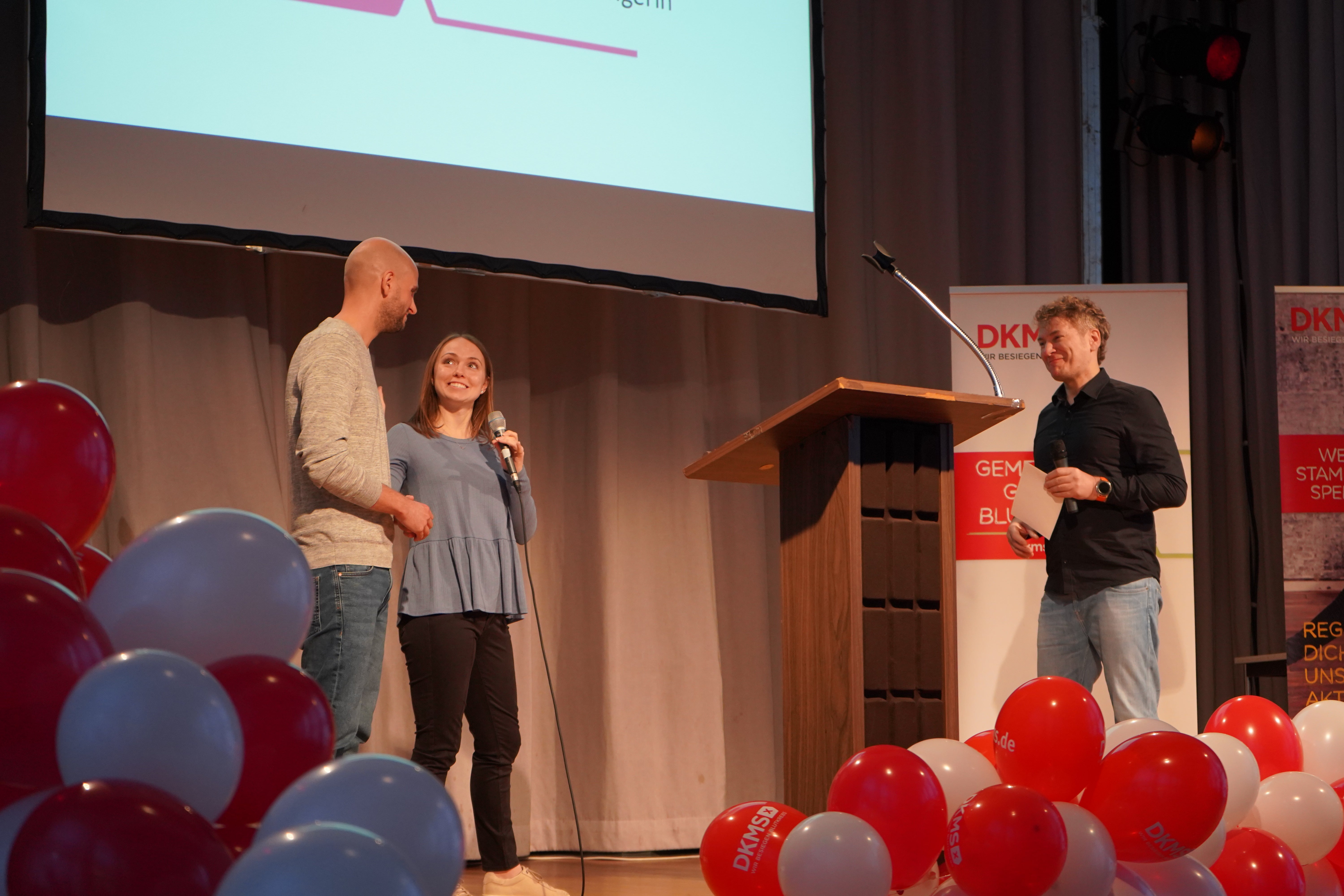 drei Menschen stehen während eines DKMS Events auf der Bühne