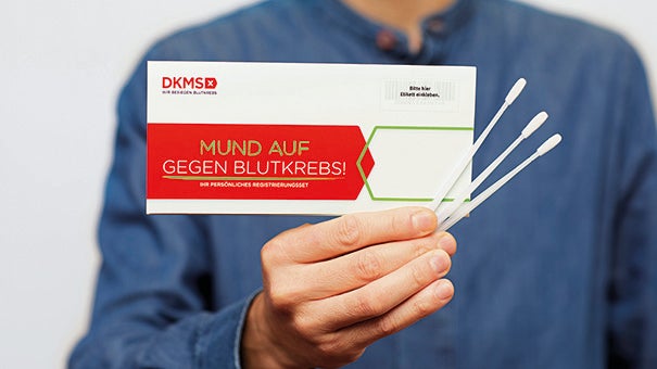 Eine Person hält ein Registrierungskit und Wattestäbchen