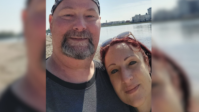 Ein Mann und eine Frau machen ein Selfie in der Sonne vor einem Gewässer. 