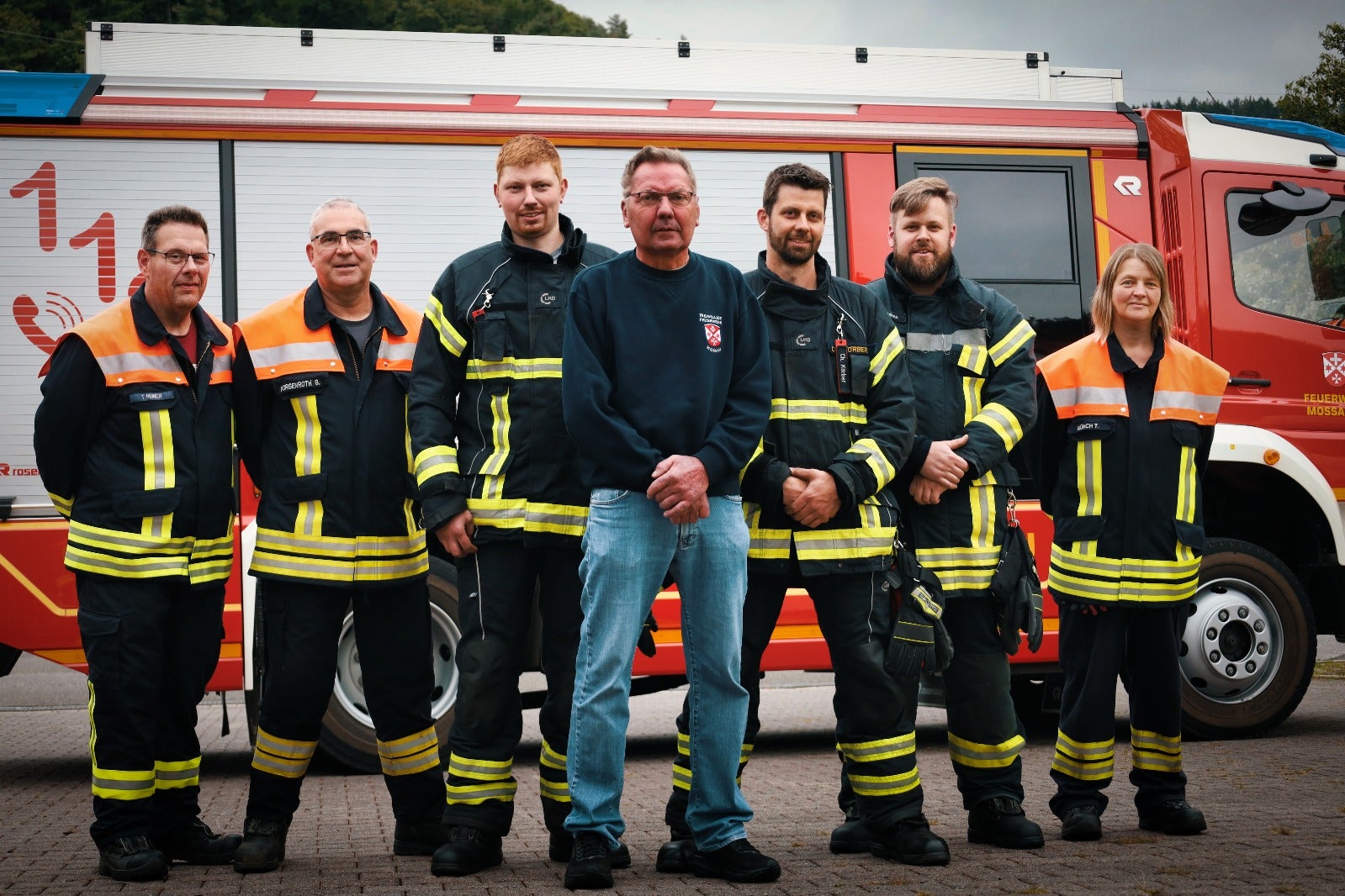 Eine Gruppe von Feuerwehrleuten steht vor einem roten Lastwagen