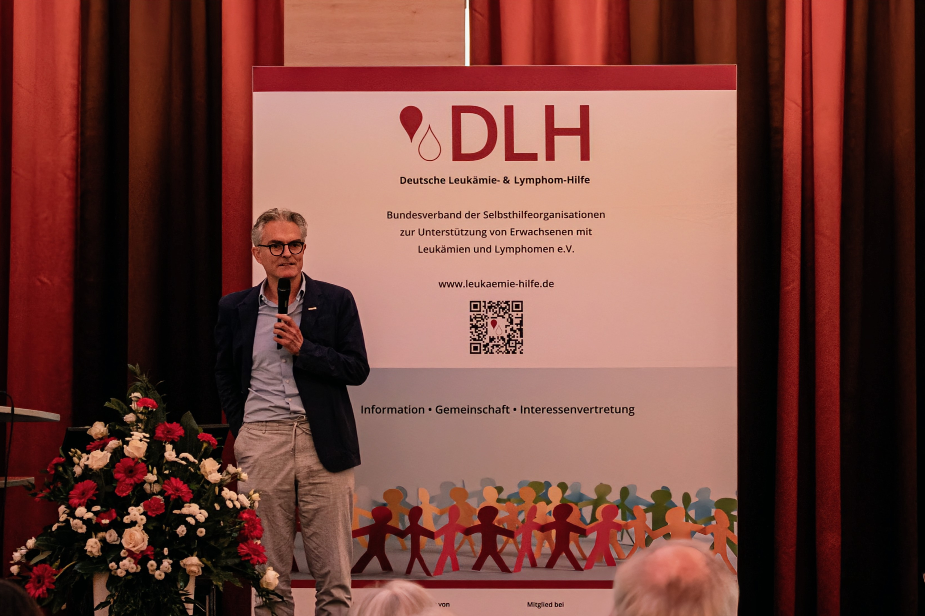 Ein Mann steht auf einer Bühne mit einem Mikrofon.