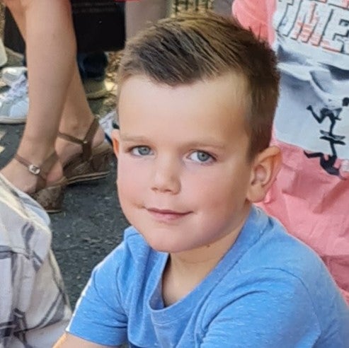 Ein Junge sitzt draußen mit einer Gruppe von Menschen