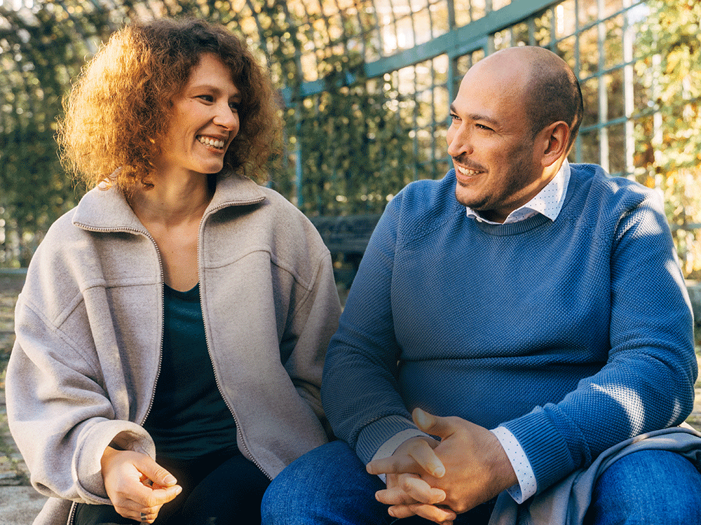 Ein Mann und eine Frau sitzen auf einer Bank. Zitat auf dem Bild: Mund auf. Stäbchen rein. Spender sein. - Ricardo & Marianne geheilter Blutkrebspatient und seine Spenderin