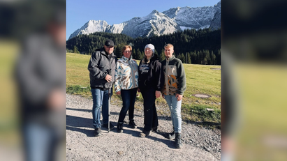 Eine Gruppe von Menschen, die auf einer Schotterstraße steht, im Hintergrund sind Berge zu sehen