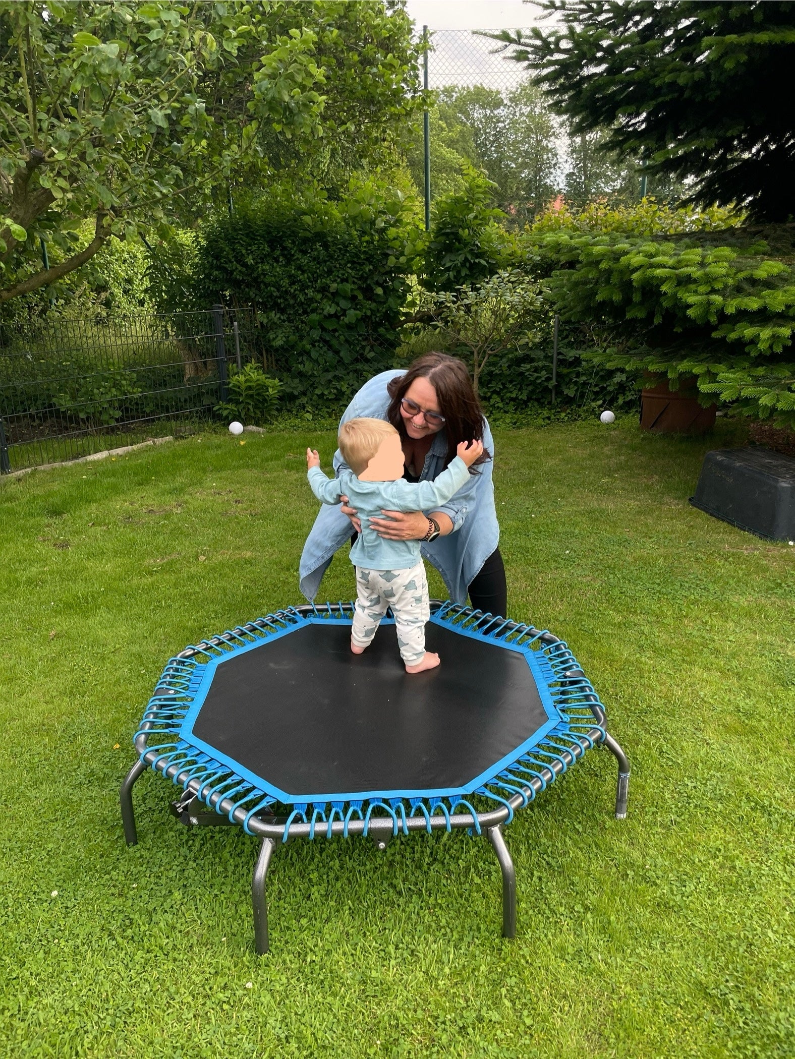 Eine Frau hält ein Baby auf einem Trampolin