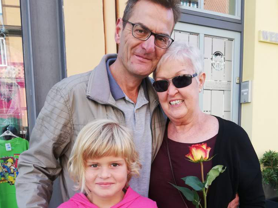 Ein Mann und eine Frau posieren für ein Foto mit einem Mädchen und einer Rose