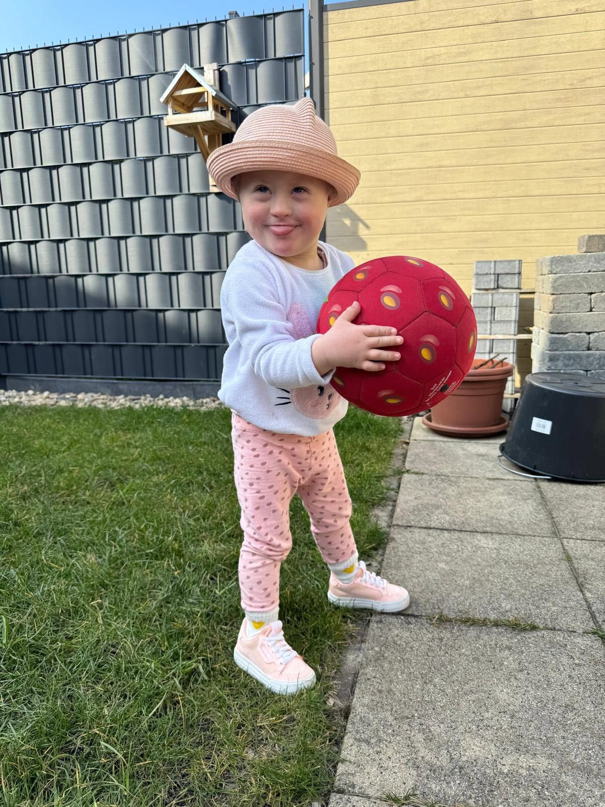 Jette hält im Garten einen Ball in den Händen und lächelt 