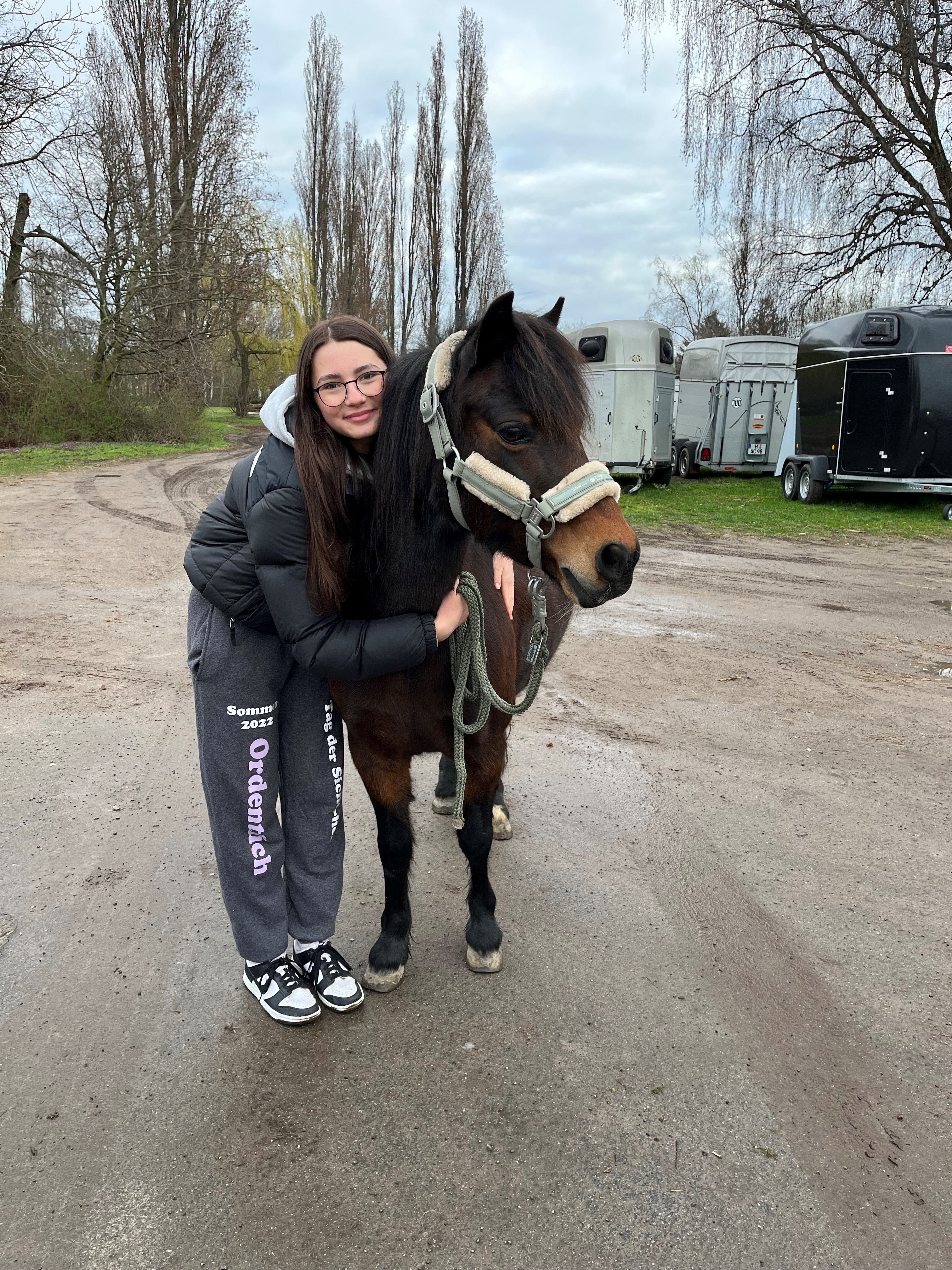 ein junges Mädchen posiert mit einem Pferd für ein Foto 