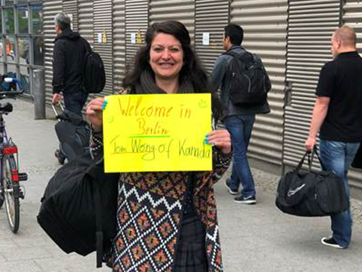 Eine Frau hält ein gelbes Schild mit "Welcome in Berlin"