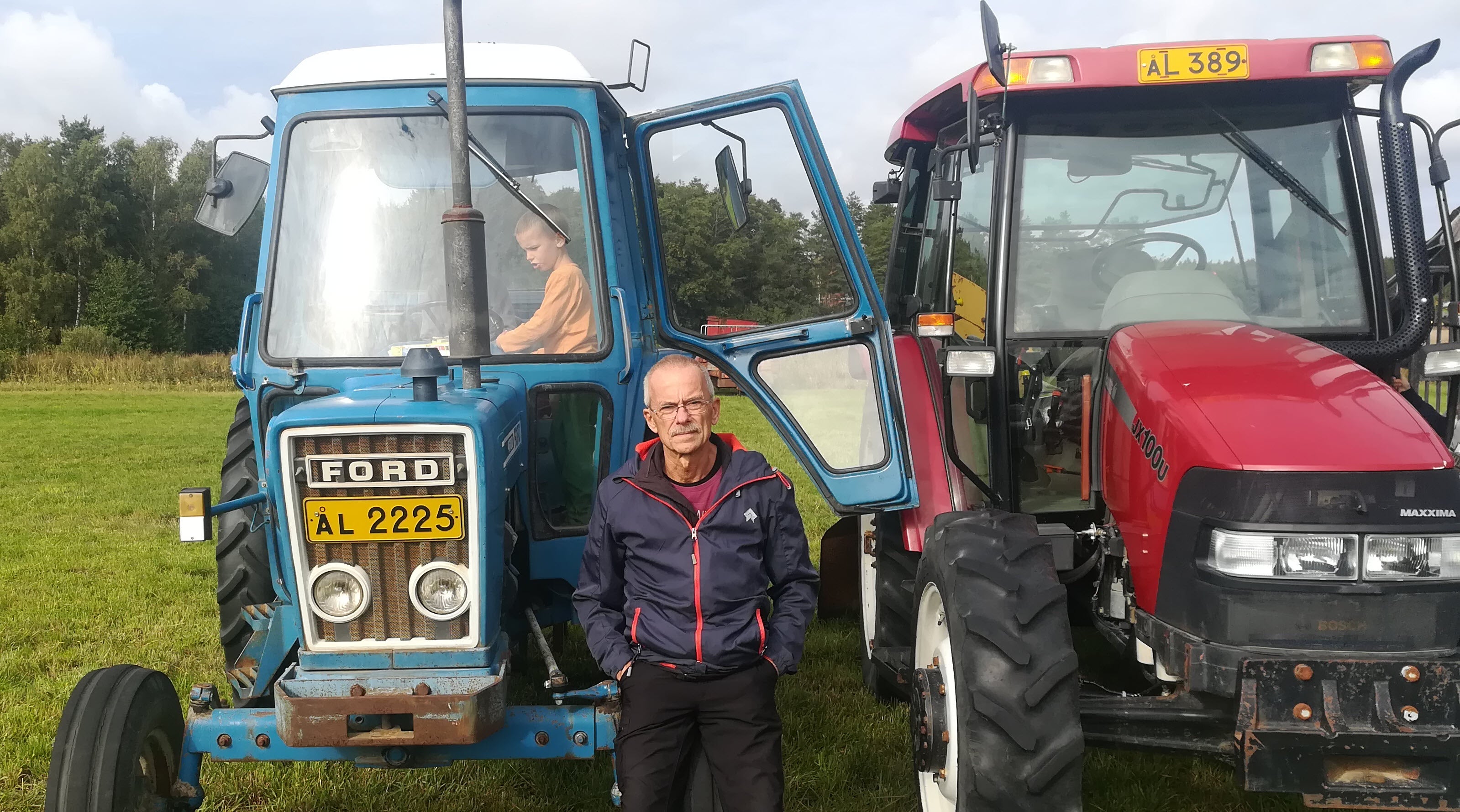 Frank steht vor zwei älteren Traktoren.