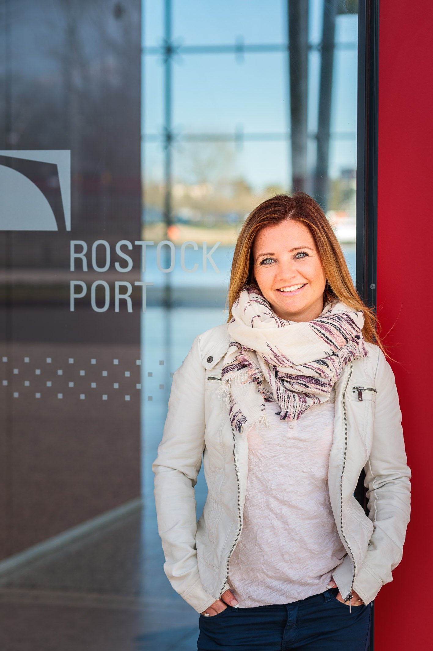 Die Rostockerin vor einer Glasscheibe und lächelt 
