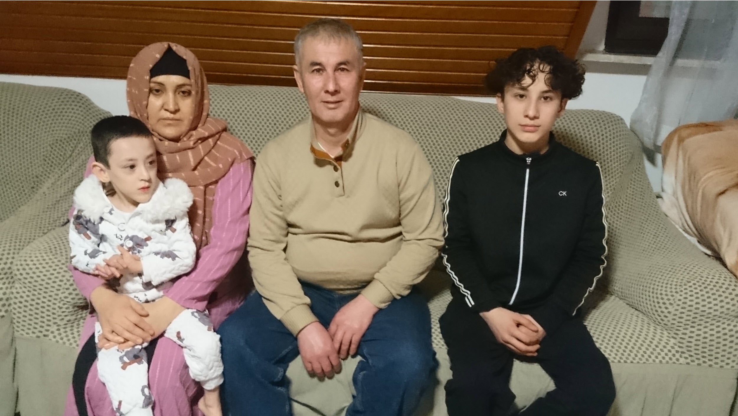 Rafia und ihre Familie sitzen auf einem Sofa.