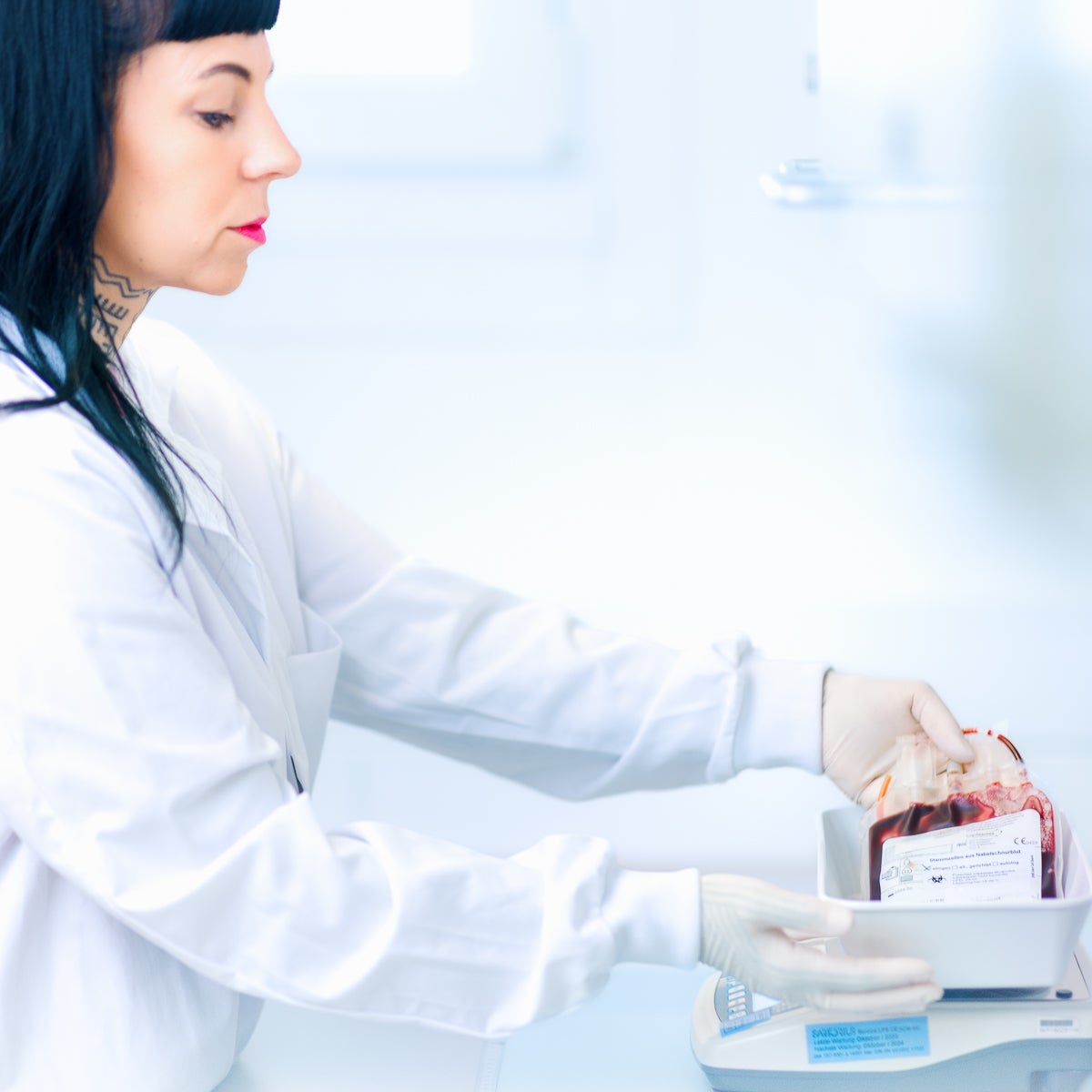 Eine Frau in einem weißen Kittel die in der Hand ein Blutbeutel hält