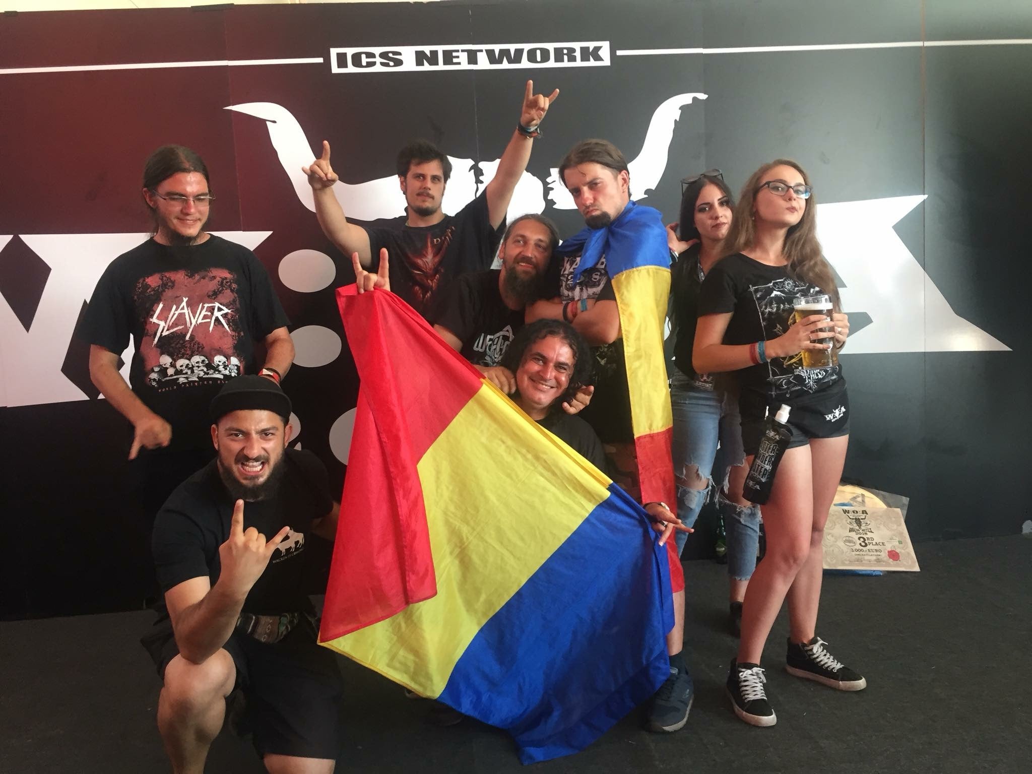 Eine Gruppe von Menschen posiert für ein Foto, im Hintergrund ist das Wacken Festival Logo zu sehen
