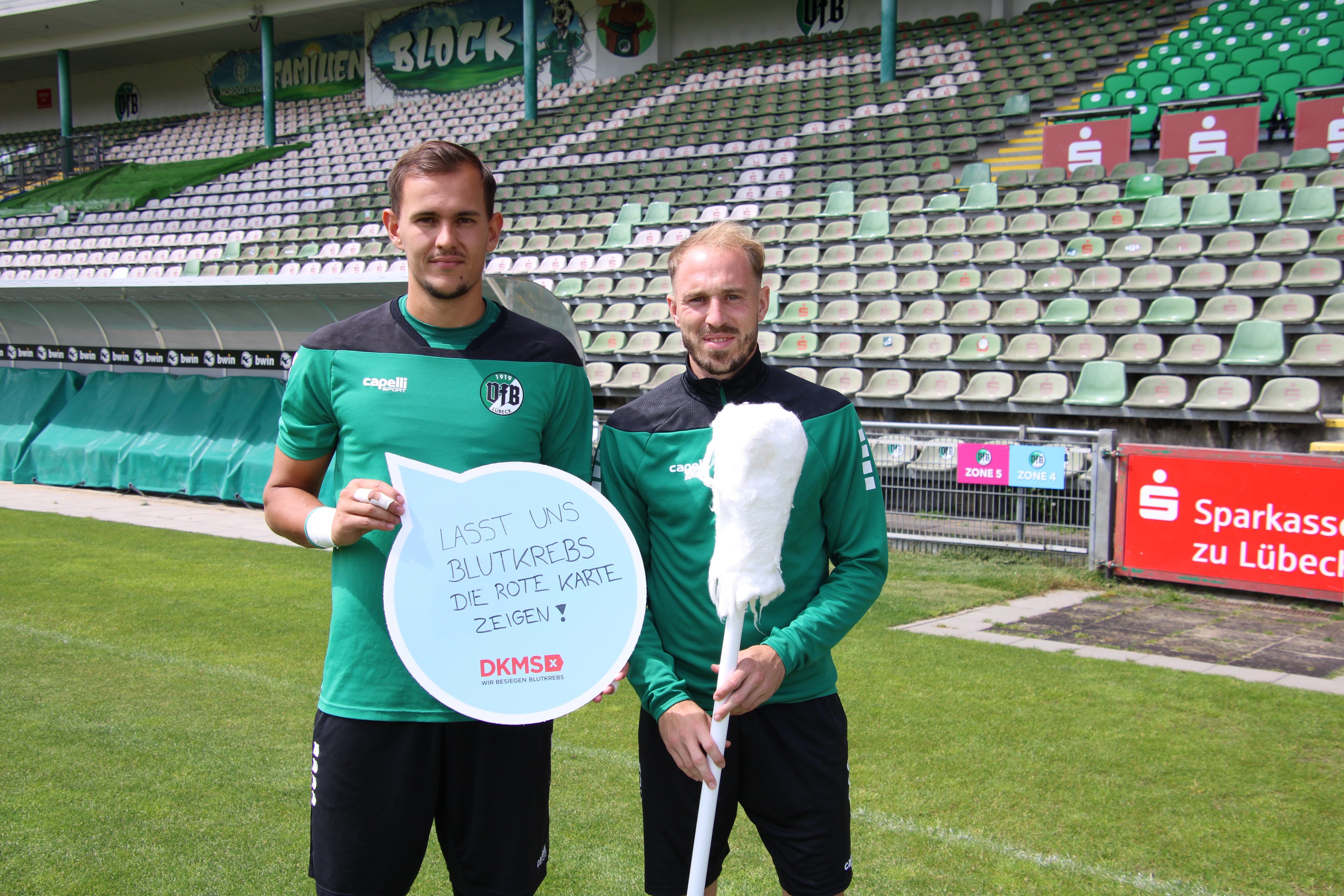 2 Spieler des VfB Lübeck mit DKMS Wattestäbchen und DKMS Schild 