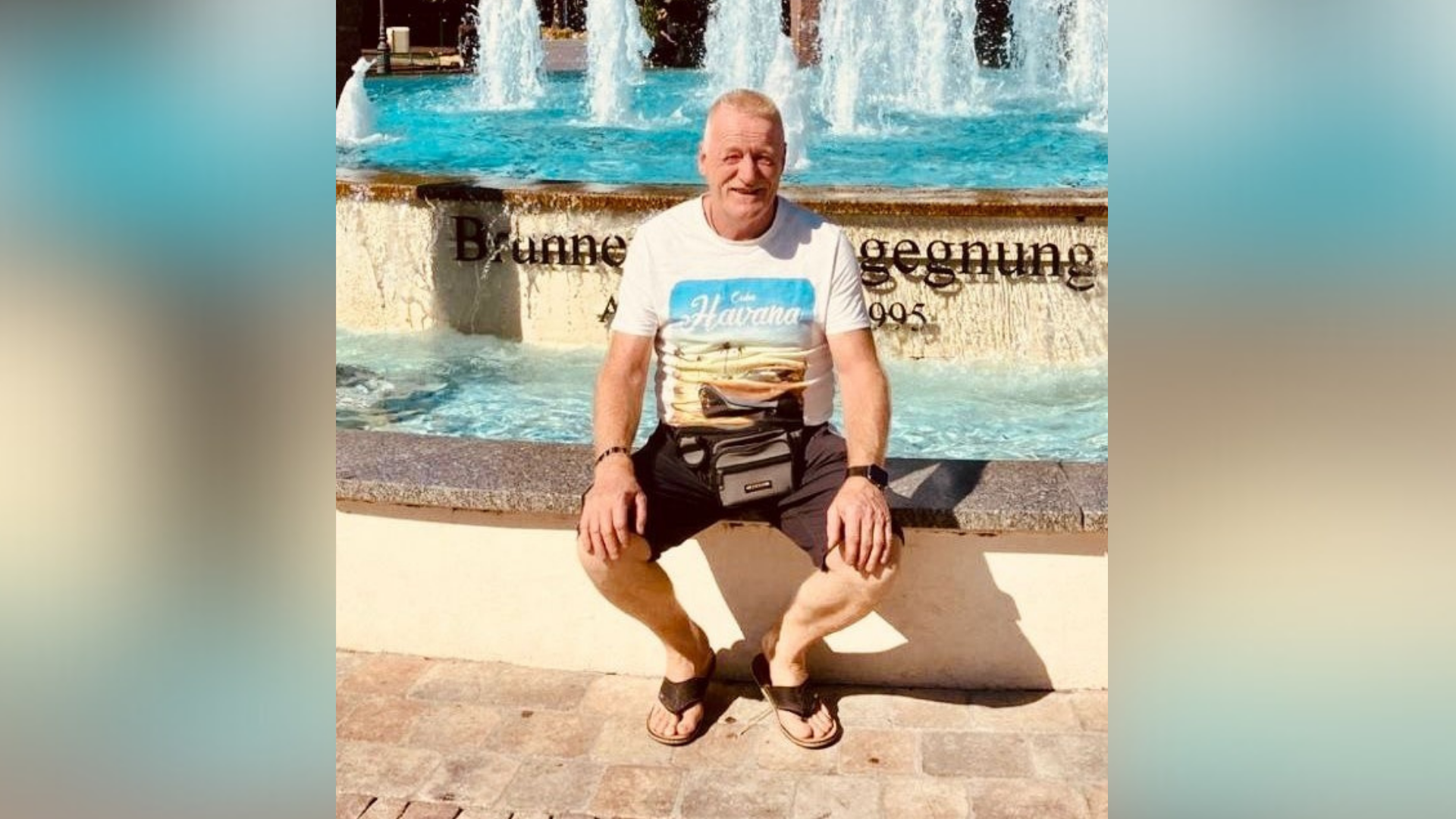 Ein Mann sitzt an einem Springbrunnen.