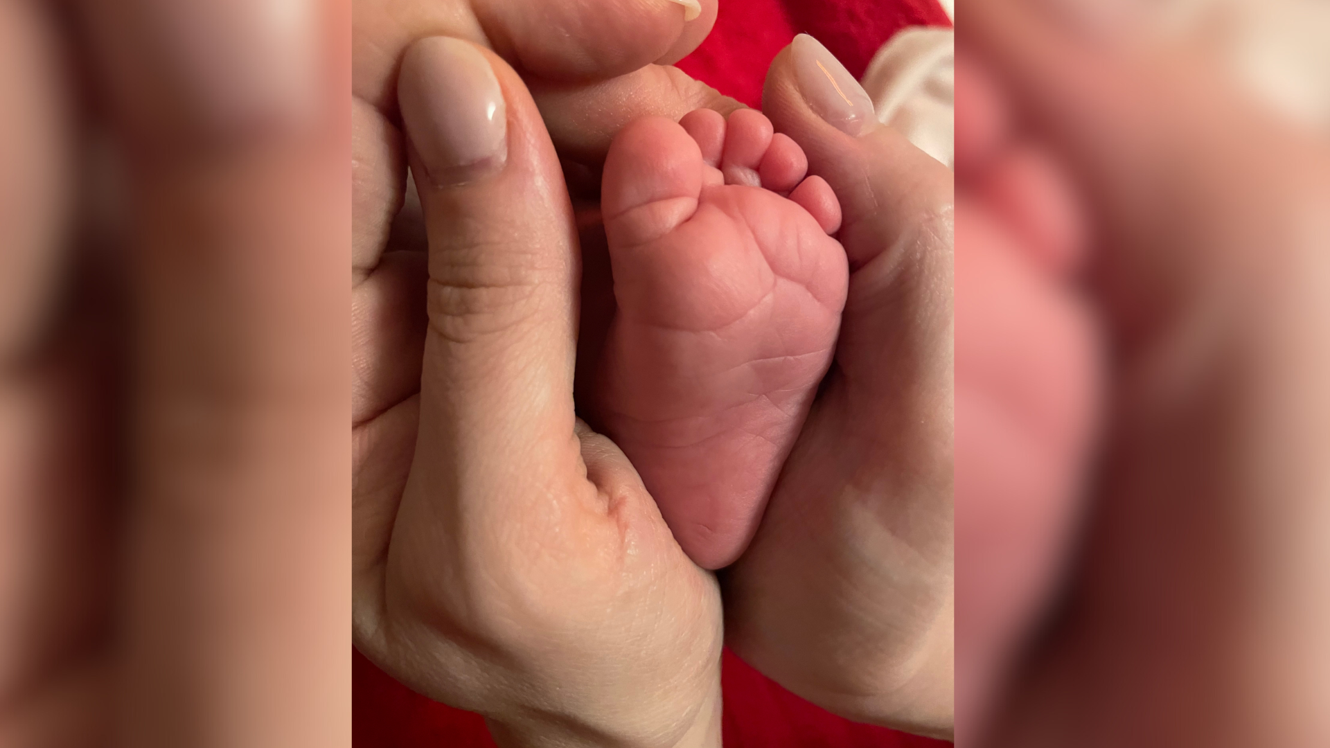 Der Fuß eines Babys in der Hand eines Menschen