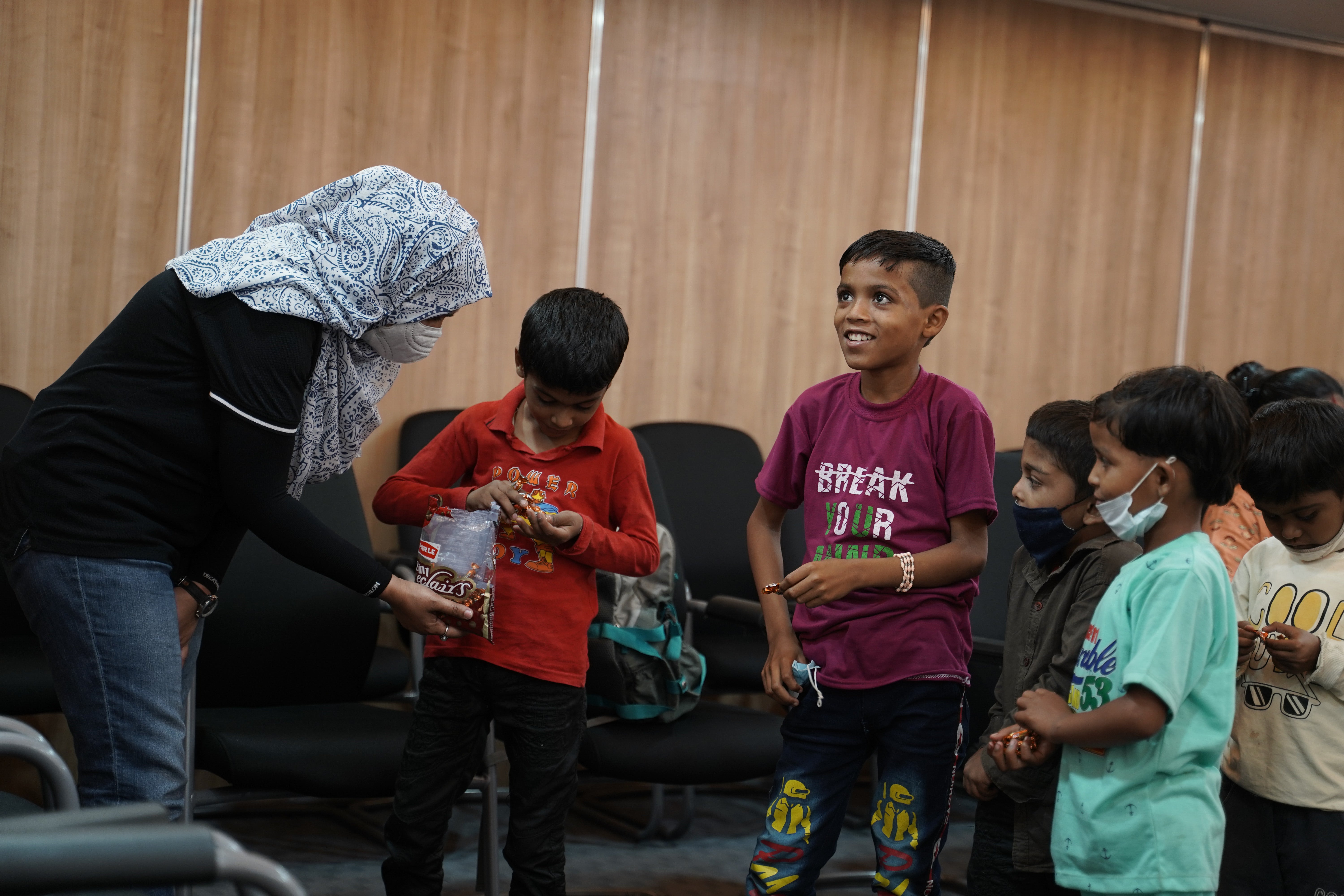 Eine Frau gibt einer Gruppe von Kindern eine Tüte mit Lebensmitteln