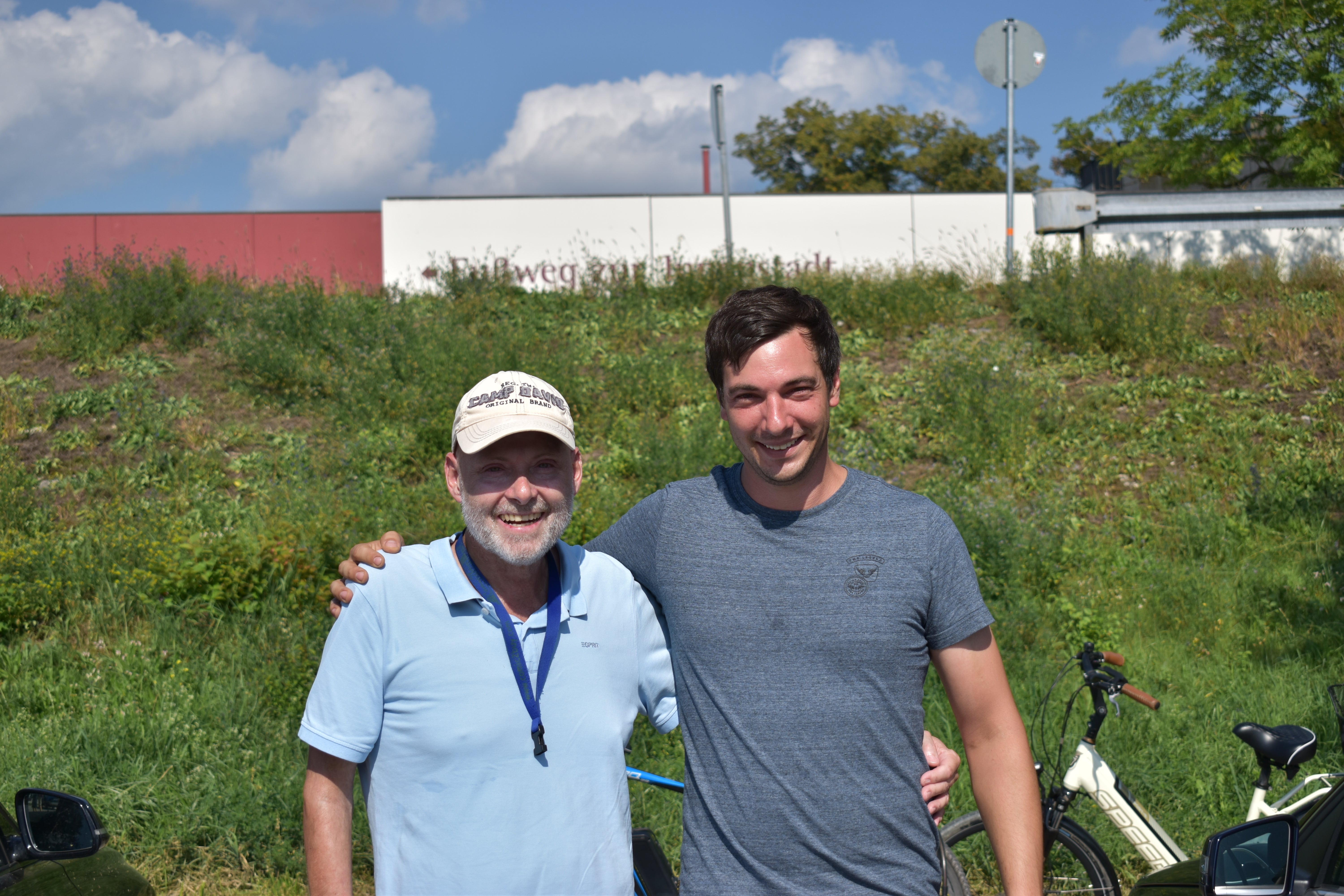 Stefan und Michael stehen nebeneinander. Sie legen beide einen Arm um den anderen.