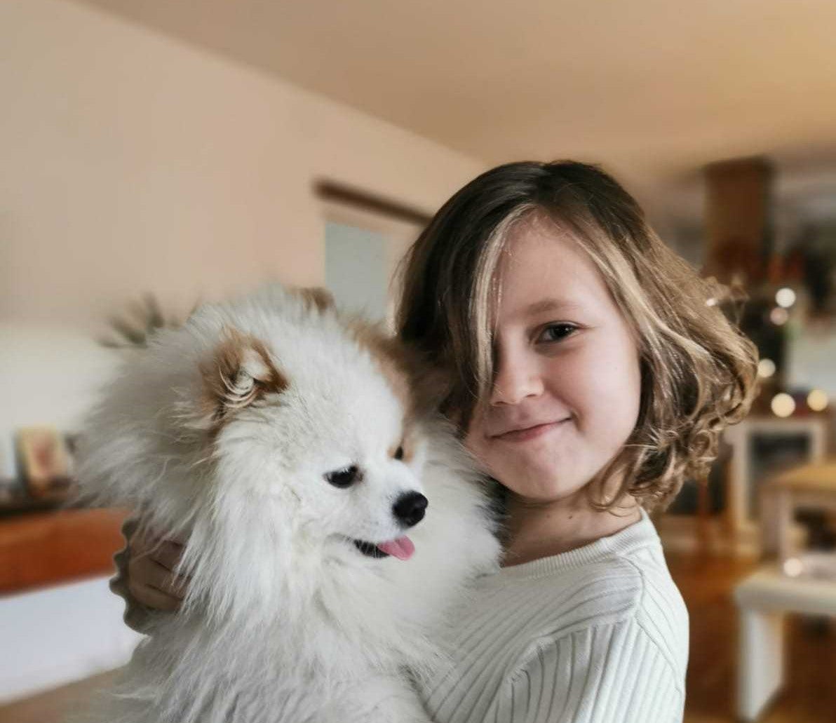 ein junges Mädchen hält ihren Hund auf dem Arm 