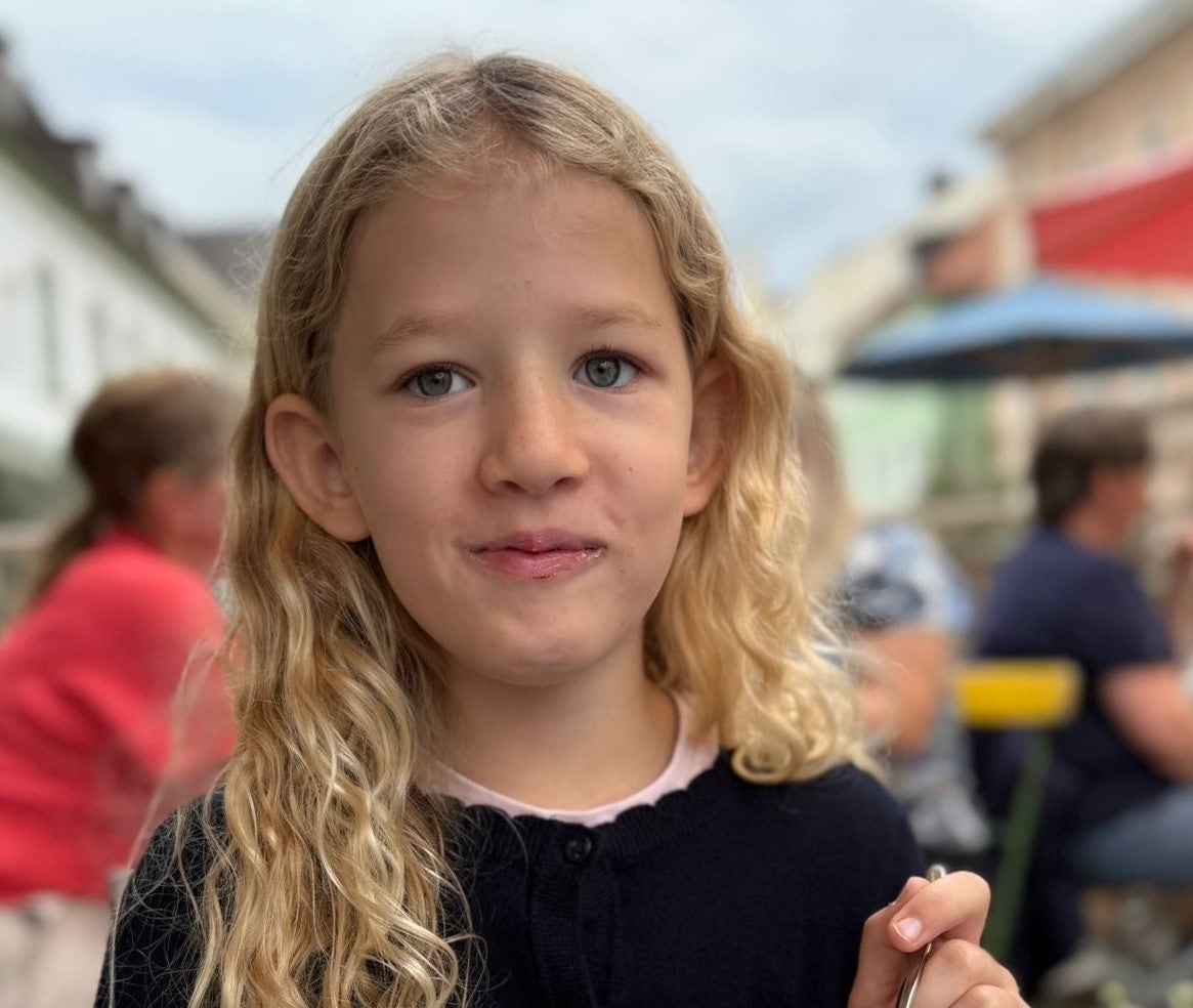 Ein Mädchen sitzt an einem Tisch und isst einen Macaron.