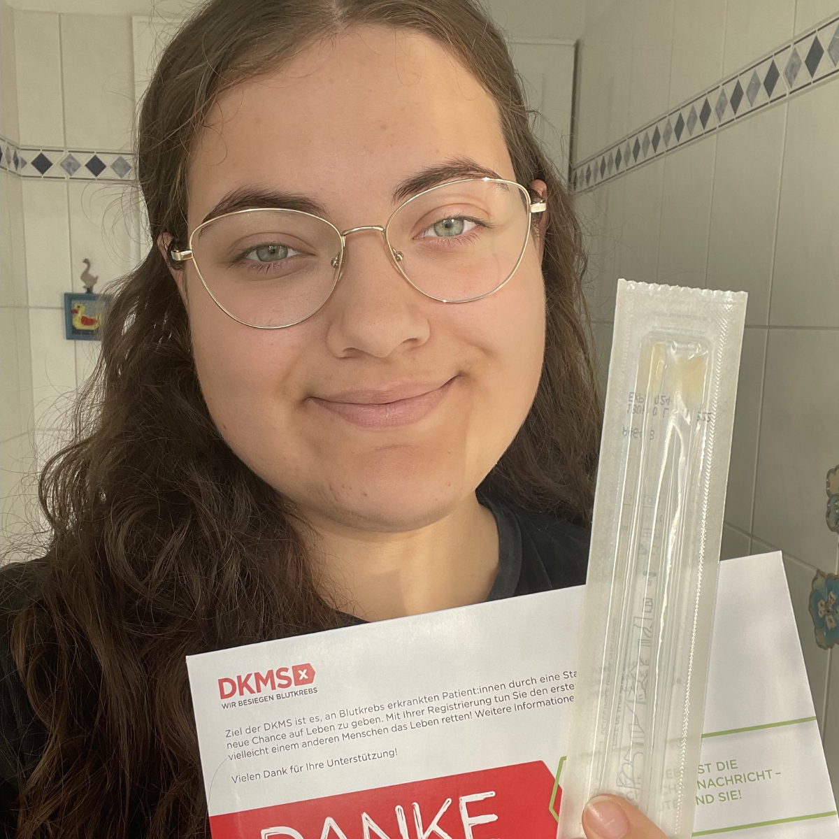 eine Frau die ein Registrierungsset in der Hand hält und ein Selfie macht