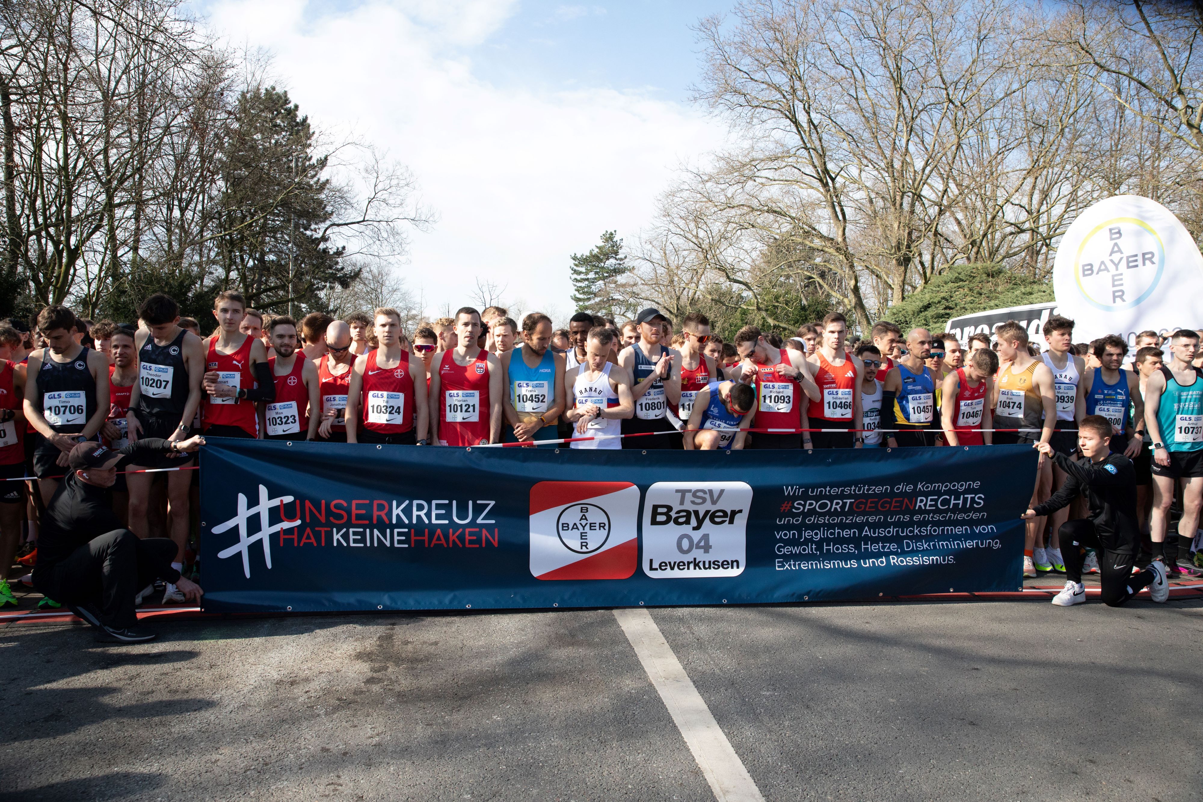 TSV Bayer 04 Leverkusen veranstaltet einen Lauf gegen rechts - viele Läufer sind am Start und halten ein Plakat hoch mit dem Slogan "Unser Kreuz hat keine Hacken"