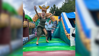 Zwei junge Frauen springen auf einer bunten Hüpfburg mit Giraffenkopf.